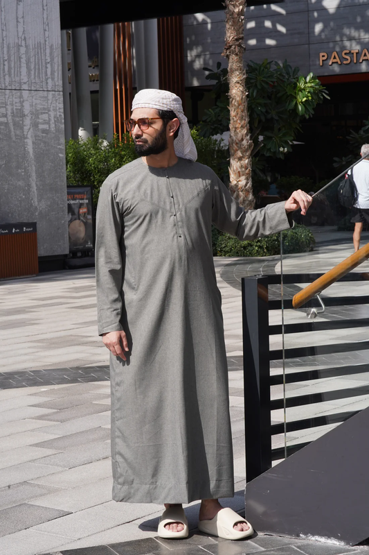 Full-length light gray Arabic thobe with functional side pockets, showcasing a blend of classic Emirati style and modern craftsmanship.